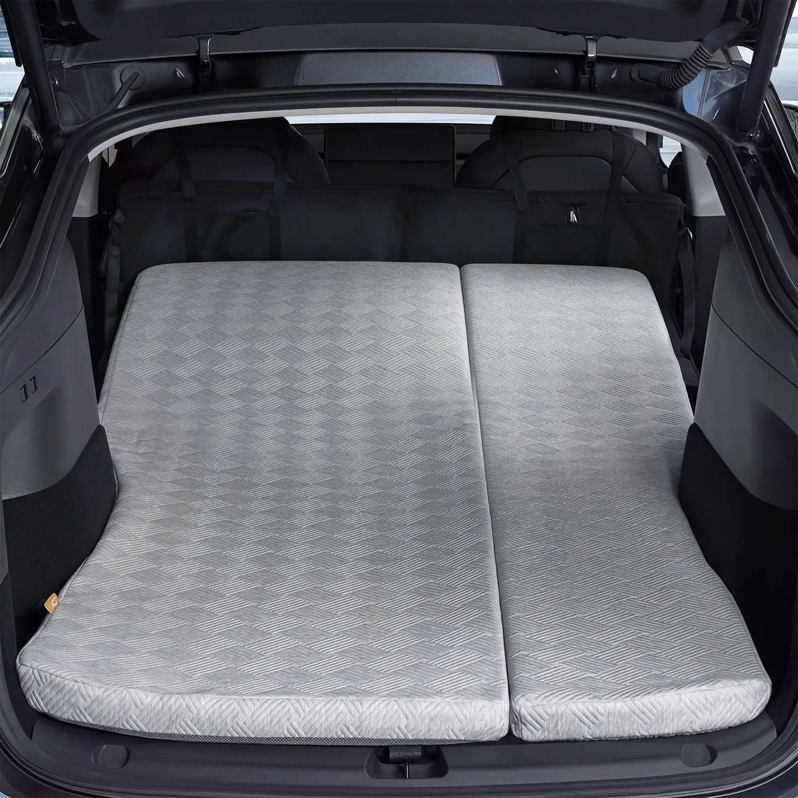 Rear view of a Tesla Model Y Juniper trunk area with the 3W custom split memory foam sleeping mattress fully extended for dual person car camping.
