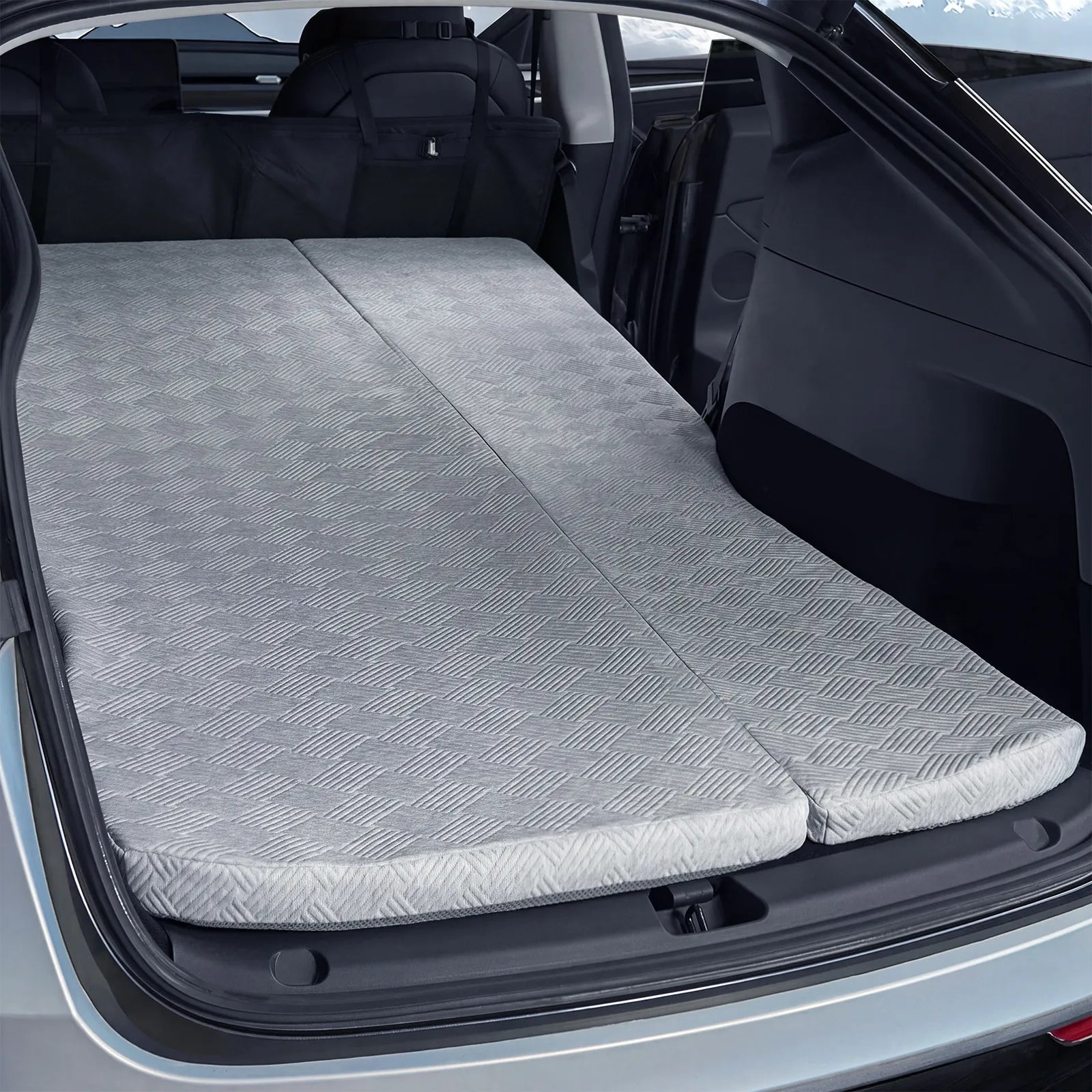 Angled view of the 3W custom fit split twin car mattress unfolded in the back of a Tesla Model Y, illustrating its flush integration with the vehicle interior.