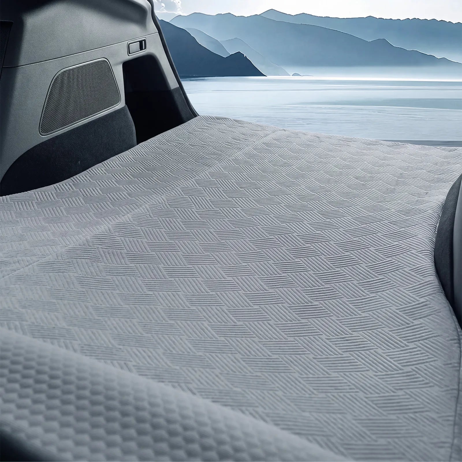Close up view of the premium breathable textured cool fabric surface of the 3W car camping bed inside a vehicle cabin near the window.